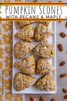 pumpkin scones with pecans and maple syrup on a white platter surrounded by pecans