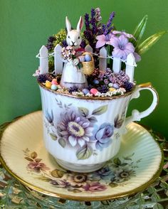 a teacup with flowers and bunny figurines in it