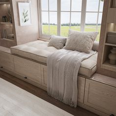 a window seat with pillows and blankets on it in front of a bookshelf