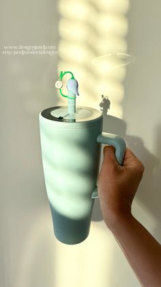 a hand holding a coffee cup with a green handle