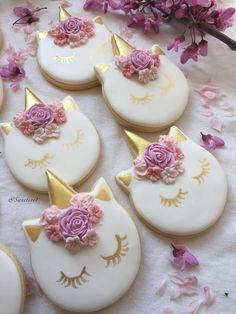 decorated cookies with pink flowers and gold unicorn ears on a table next to purple flowers