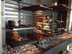 an oven with food cooking in it and some racks on the wall behind it that are full of meats