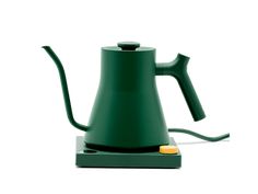 a green tea kettle sitting on top of a metal stand with a yellow cup next to it