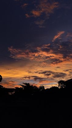 the sun is setting over some trees and buildings