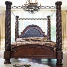 a bed with four posts and a chandelier hanging from it's ceiling