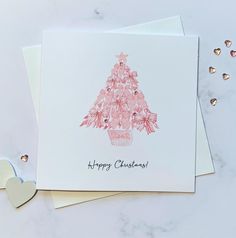 a card with a christmas tree on it and two hearts next to it, which says happy christmas