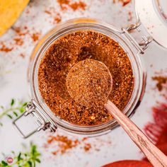 a jar filled with spices next to an apple