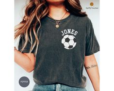 a woman wearing a black shirt with a soccer ball on the front and white lettering that says jones