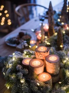 candles are arranged in the middle of a wreath with evergreen branches and pine cones on it