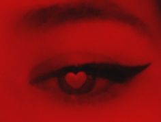 a woman's eye with a red heart in the middle of her irise