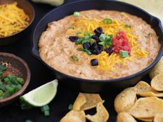 a black bowl filled with dip surrounded by chips