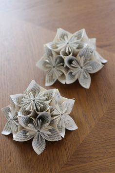 two origami flowers sitting on top of a wooden table