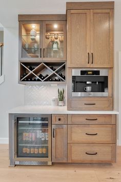 a kitchen with wooden cabinets and white counter tops, an open wine cooler in the middle