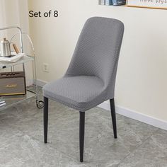 a gray chair sitting in front of a white wall next to a shelf with pictures on it