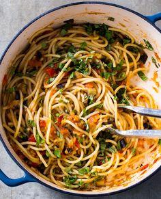 a large pot filled with pasta and garnished with parsley on the side