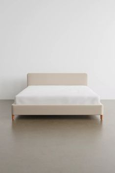 a white bed sitting on top of a floor next to a wooden headboard and foot board