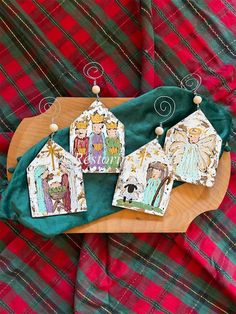 three ornaments are sitting on top of a wooden tray with tartan plaid fabric behind them