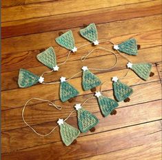 knitted christmas tree ornaments are arranged on a wooden floor with string attached to them