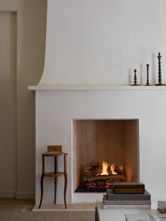 a fire place in a living room next to a chair and table with books on it