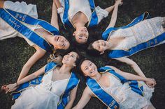 four young women in blue and white dresses laying on the ground with their arms around each other