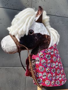 a stuffed horse wearing a pink and white dress with flowers on it's head