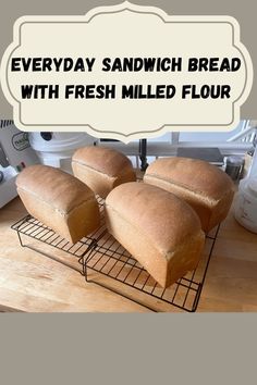 three loaves of bread sitting on top of a cooling rack with the words everyday sandwich bread with fresh milled flour