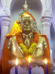 a statue with candles in front of it and a person sitting on the other side