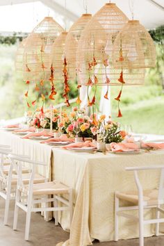 a table set up with flowers and birds hanging from the ceiling