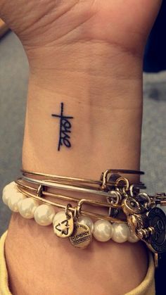 a woman's wrist with three bracelets and an anchor tattoo on the wrist