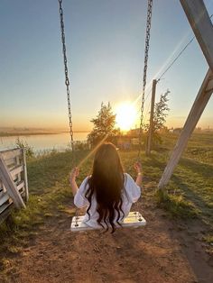 a woman sitting on a swing at sunset