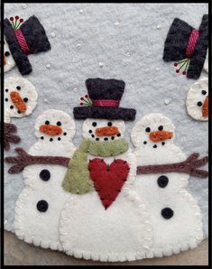 a group of snowmen with hats and scarves on their heads, one holding a heart