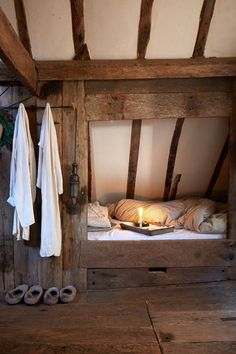 a bed in a room with wooden walls and beams on the ceiling is lit by a candle