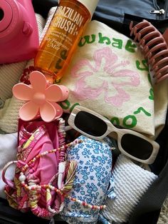 an open suitcase with clothing, sunglasses and other items in it on top of a rug