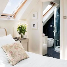 there is a white bed in the corner of this room with a skylight above it