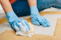 a person in blue gloves cleaning the floor with a sponge on it's surface