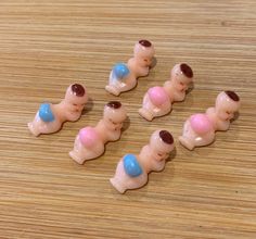 six small toy bears with pink, blue and white frosting on their backs sitting on a wooden surface