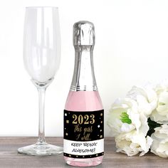 a bottle of champagne next to a wine glass on a wooden table with white flowers