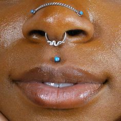 a close up of a woman's nose with piercings on top of her nose