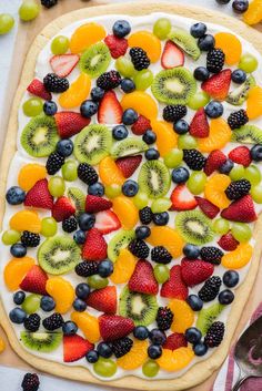 fresh fruit pizza on a cutting board with berries, kiwis, and grapes