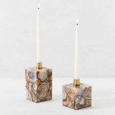 two marble candle holders with white candles in them