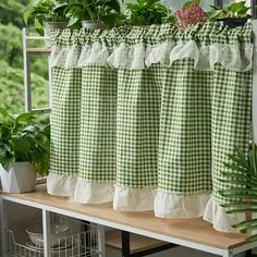 a green and white checkered shower curtain with potted plants on the shelf next to it