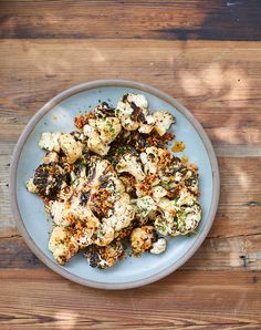 a blue plate topped with cauliflower on top of a wooden table