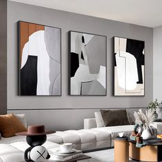 three abstract paintings hang on the wall above a white couch in a modern living room