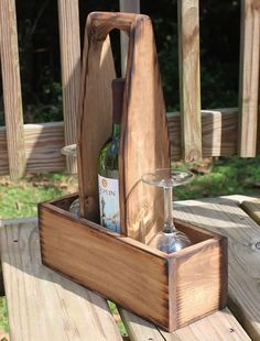 a wine bottle and glass in a wooden box on a picnic table with wood slats