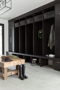 a wooden bench sitting in front of a black coat rack filled with coats and boots