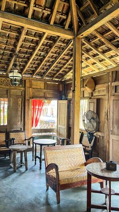 the inside of an old wooden building with chairs and tables in it, including a fan