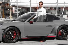 a man standing next to a gray sports car