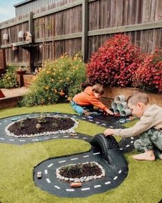 two young boys playing with toy cars in the yard