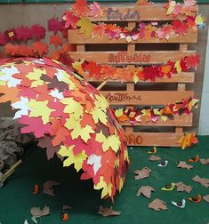 an umbrella made out of leaves sitting in front of wooden pallets with writing on them