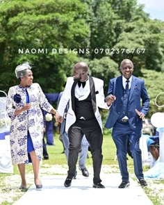 three men in suits and ties walking down the aisle at an outdoor wedding ceremony,